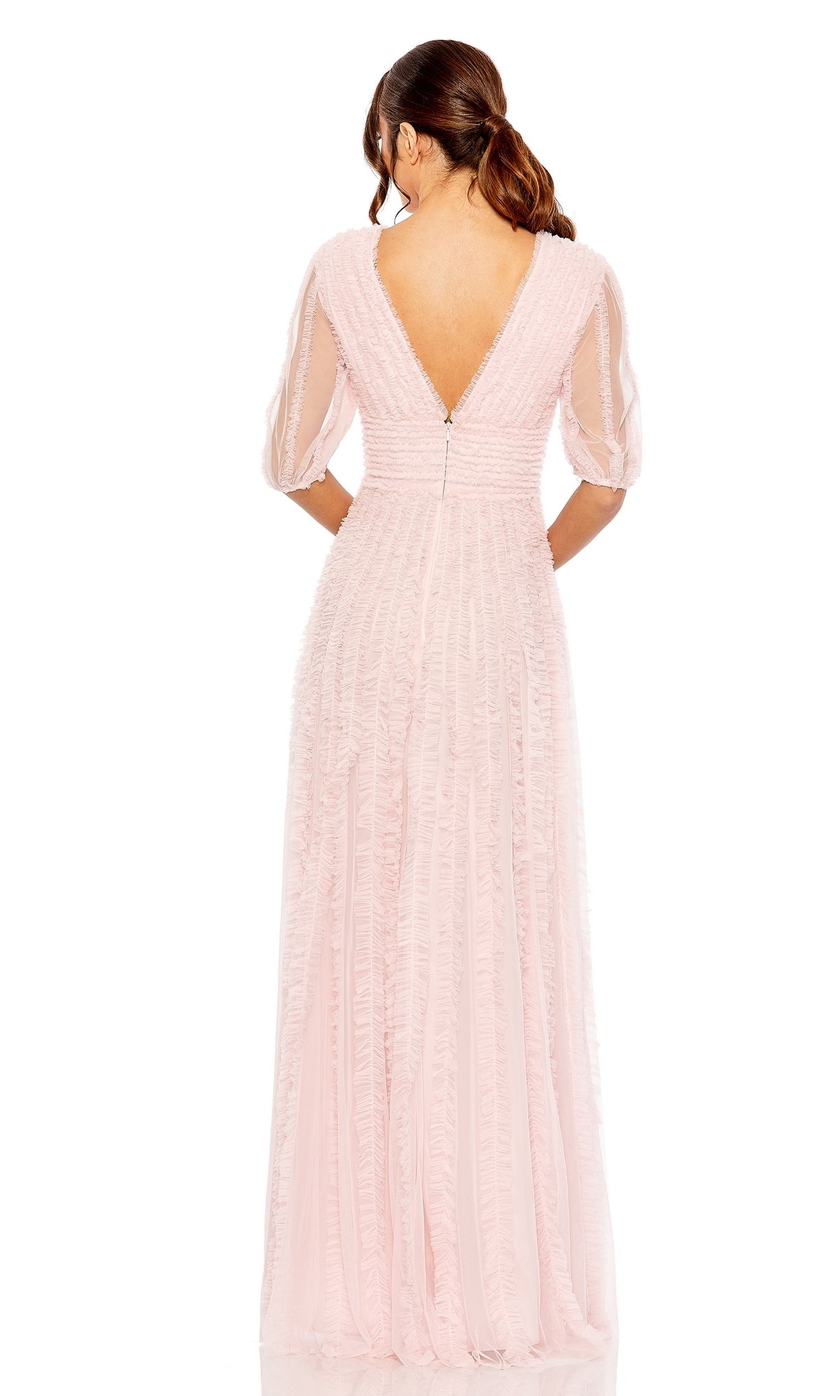 A woman stands facing away, wearing the floor-length Long Formal Dress 8050 by Mac Duggal in light pink, featuring an a-line silhouette, short sheer sleeves, and a V-shaped back.